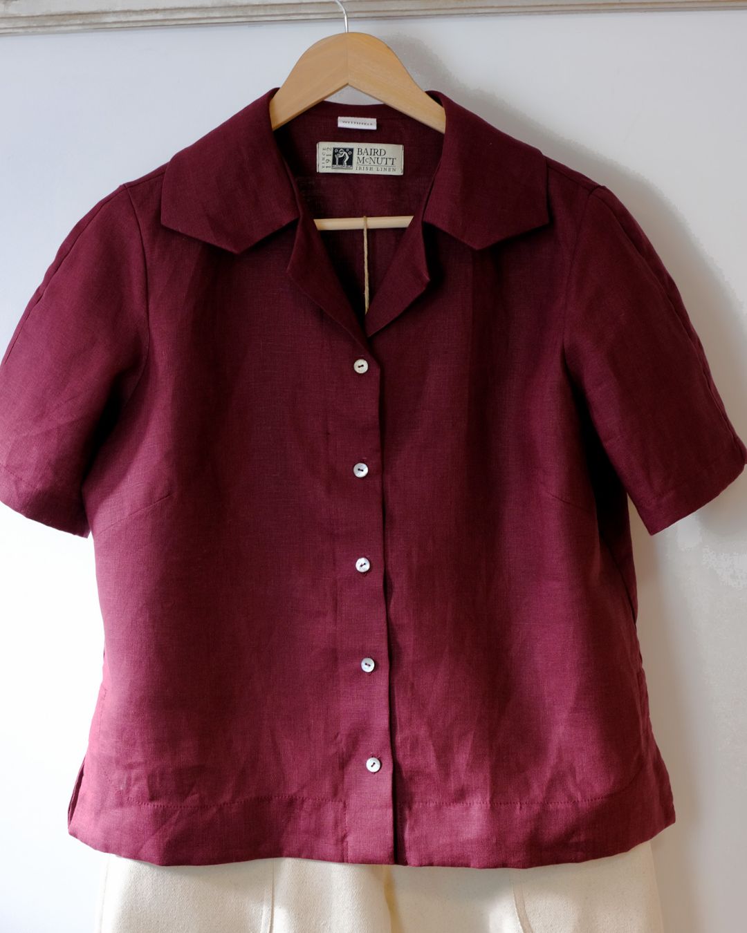 Maroon shirt on a hanger against a white wall