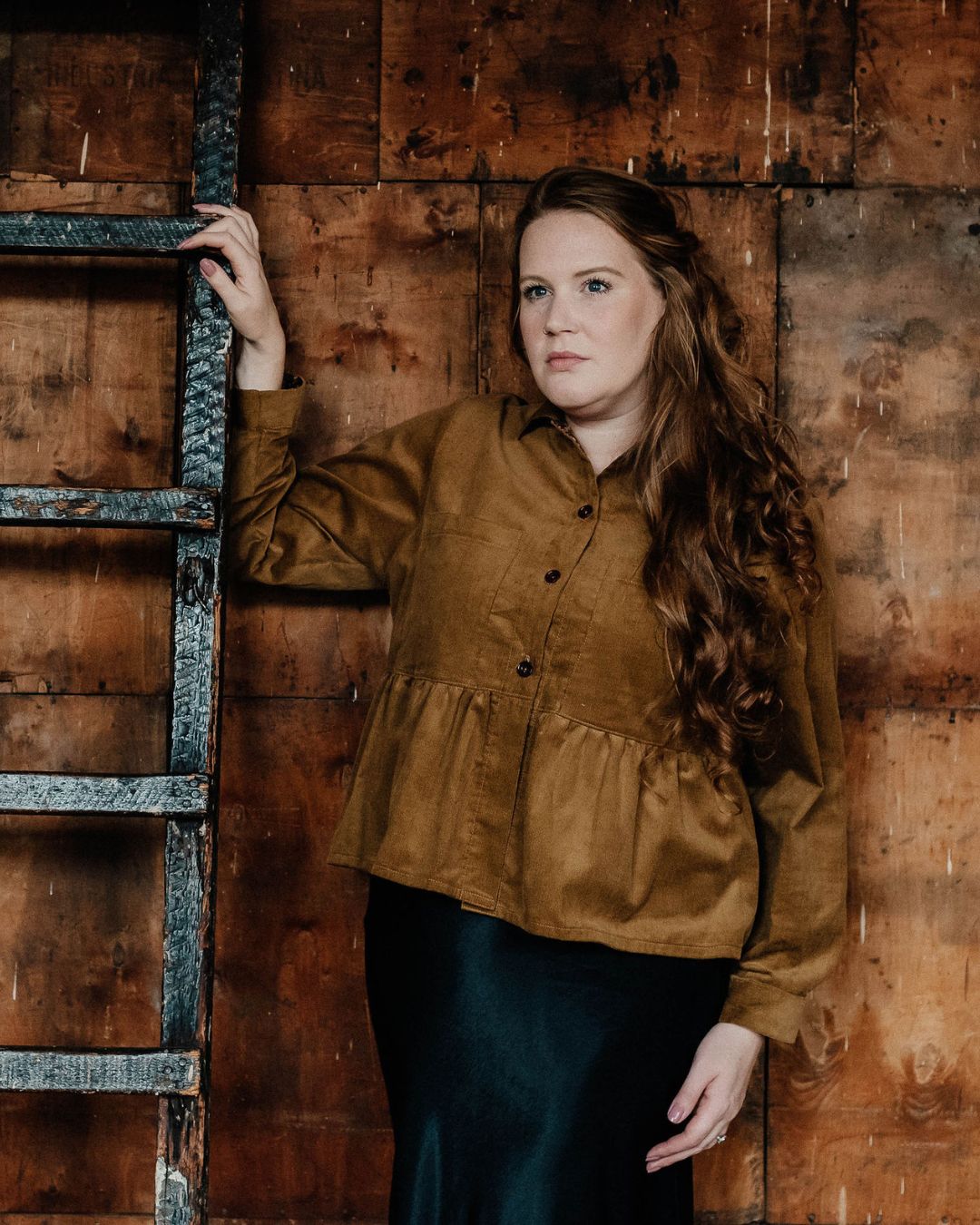 A person modeling a brown needlecord shirt with patch pockets, a neat collar with a contrast floral print, and bracelet length sleeves finished with a cuff.