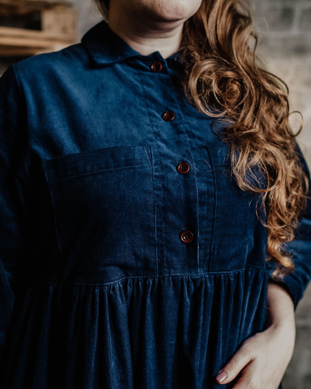 A person modeling a navy  needlecord shirt with patch pockets, a neat collar with a contrast floral print, and bracelet length sleeves finished with a cuff.