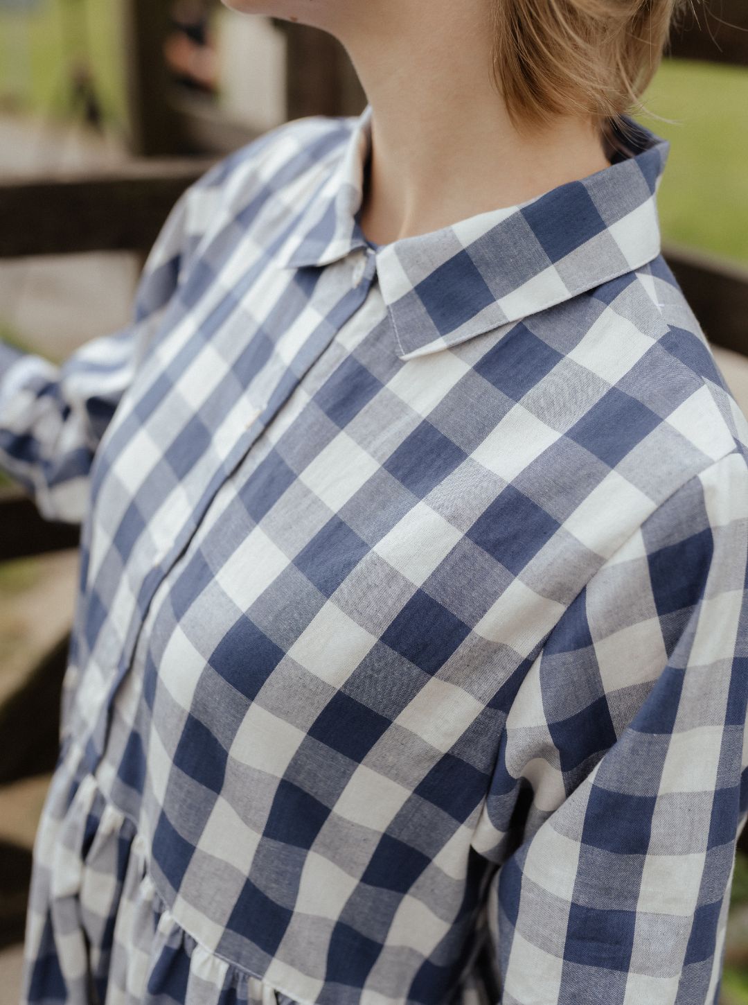Person wearing a blue and white checkered shirt with a blurred background