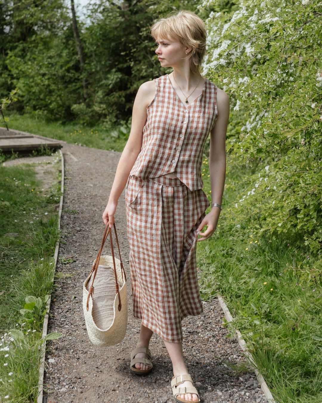 Woman in a checkered dress walking along a path in a garden