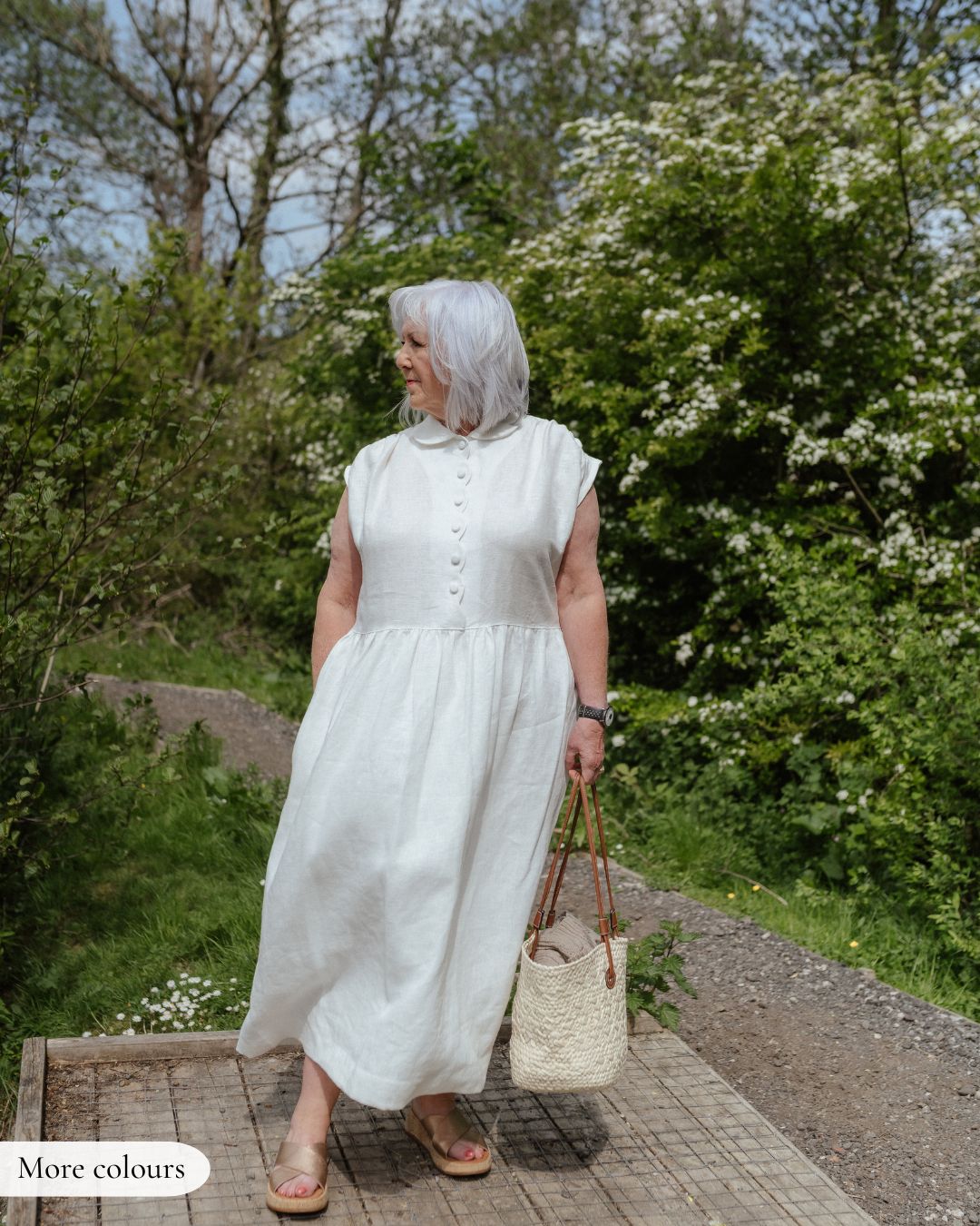 model wearing White linen dress with scalloped detail and covered button fastening.
