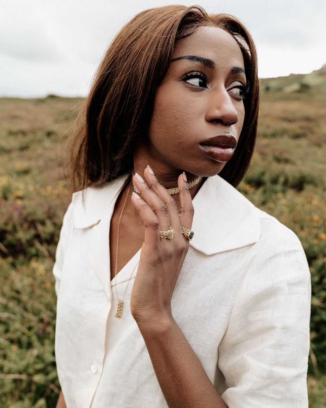 Woman wearing a cream linen blouse standing in a moorland setting.