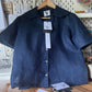Navy blue shirt on a hanger with a tag in a workshop setting