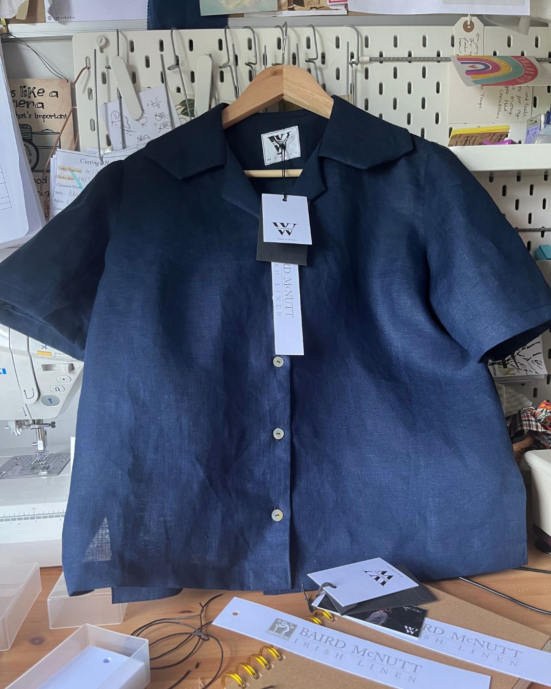 Navy blue shirt on a hanger with a tag in a workshop setting