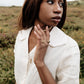 Woman wearing a white outfit with jewelry in a natural setting