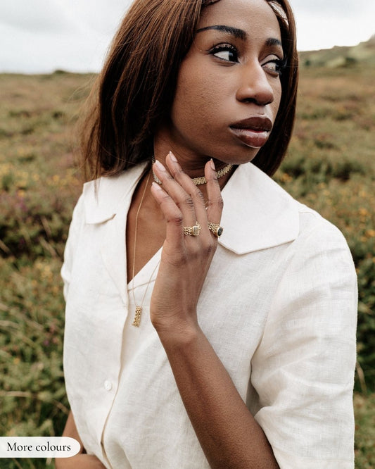 Woman wearing a white outfit with jewelry in a natural setting
