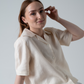 Woman wearing a cream linen blouse  sitting down in studio