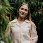 Woman wearing a cream linen blouse  standing holding hair in a moorland setting