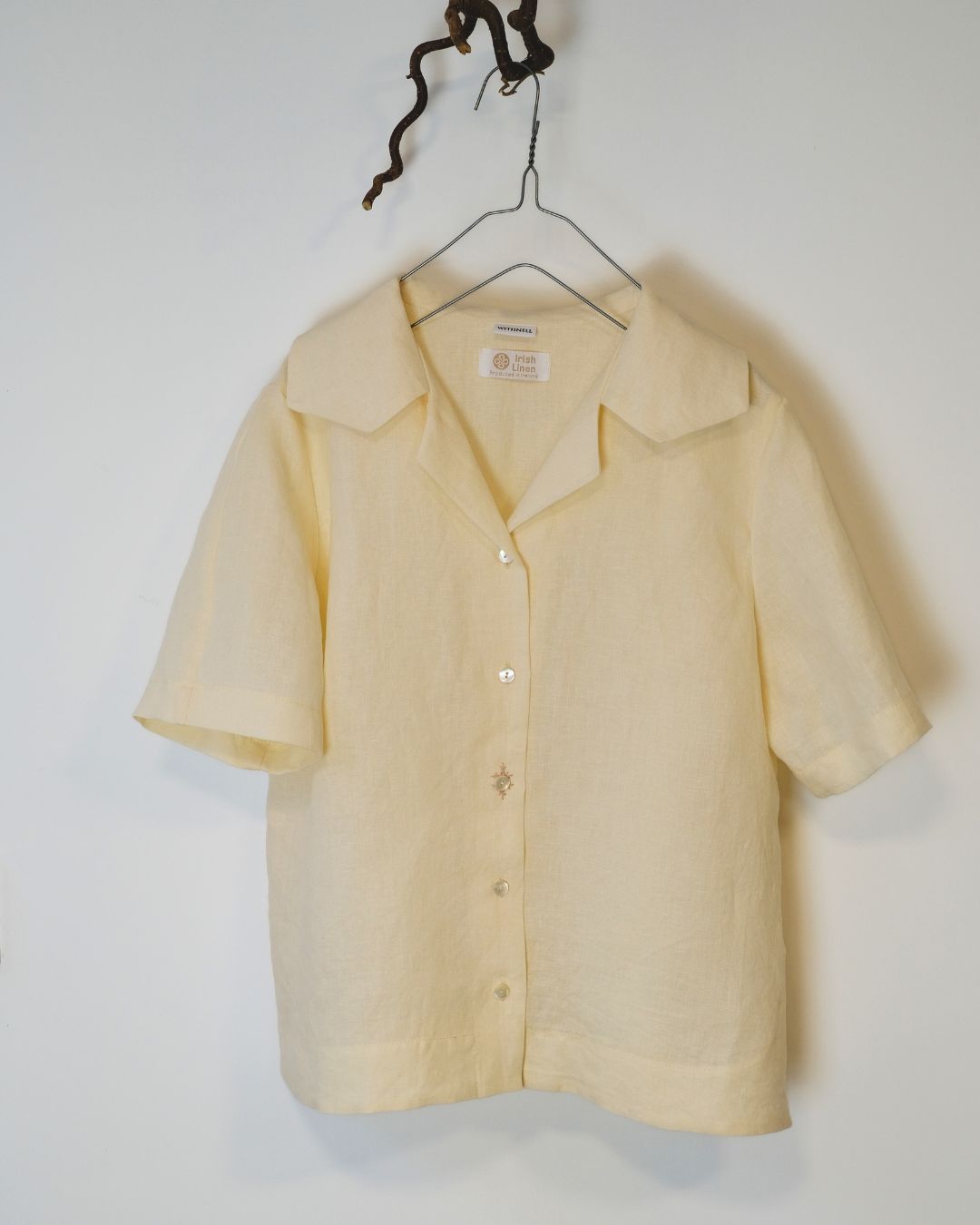 Ivory  short-sleeve shirt on a hanger against a white background
