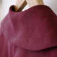 Close-up of a burgundy fabric collar on a wooden hanger with a blurred background