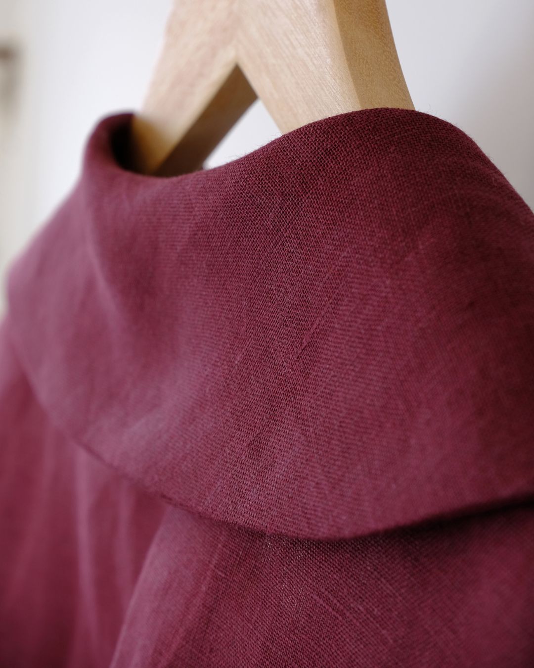 Close-up of a burgundy fabric collar on a wooden hanger with a blurred background