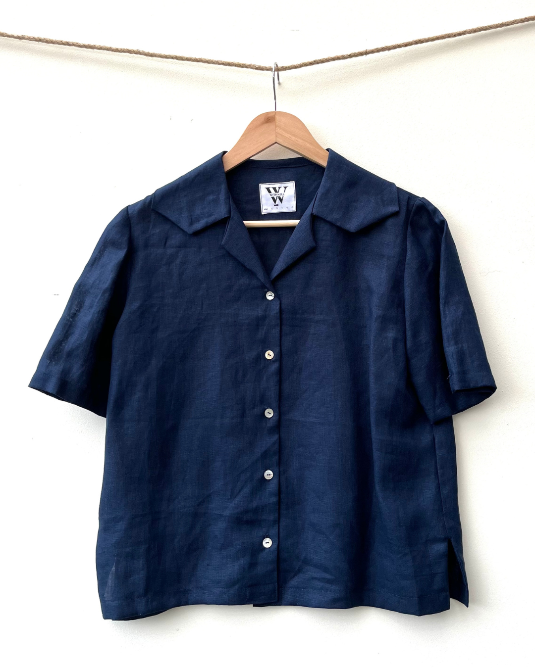 indigo linen blouse on coat hanger, hanging from a rope