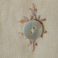 Button with decorative leaves on a beige fabric background