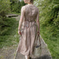 Woman in a checkered dress walking along a path in a garden