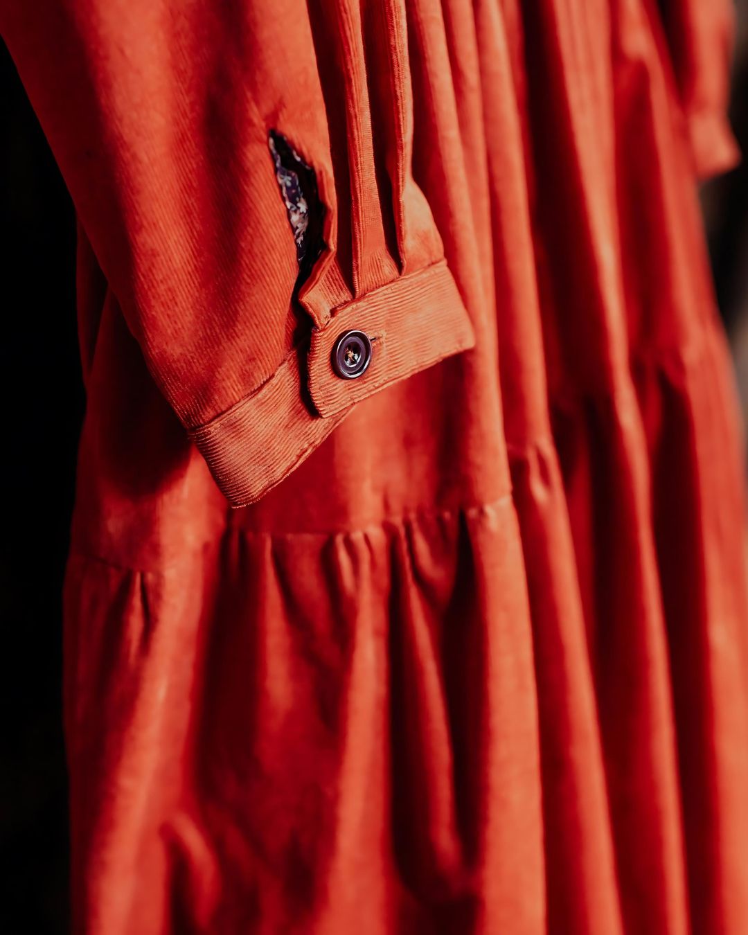 orange cordoroy dress detail showing cuff with floral trim.