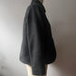 A dark gray textured wool jacket displayed on a cream-colored dress form mannequin against a neutral light gray wall.