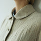 Close-up of a person wearing a textured linen jacket from Withnell with a collar and front buttons, layered over a light blue shirt.