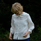 Person wearing a white blouse with a Peter Pan collar in a natural setting.