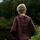 Person wearing a maroon jacket standing in a forested area