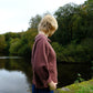 Person standing by a lake with trees in the background