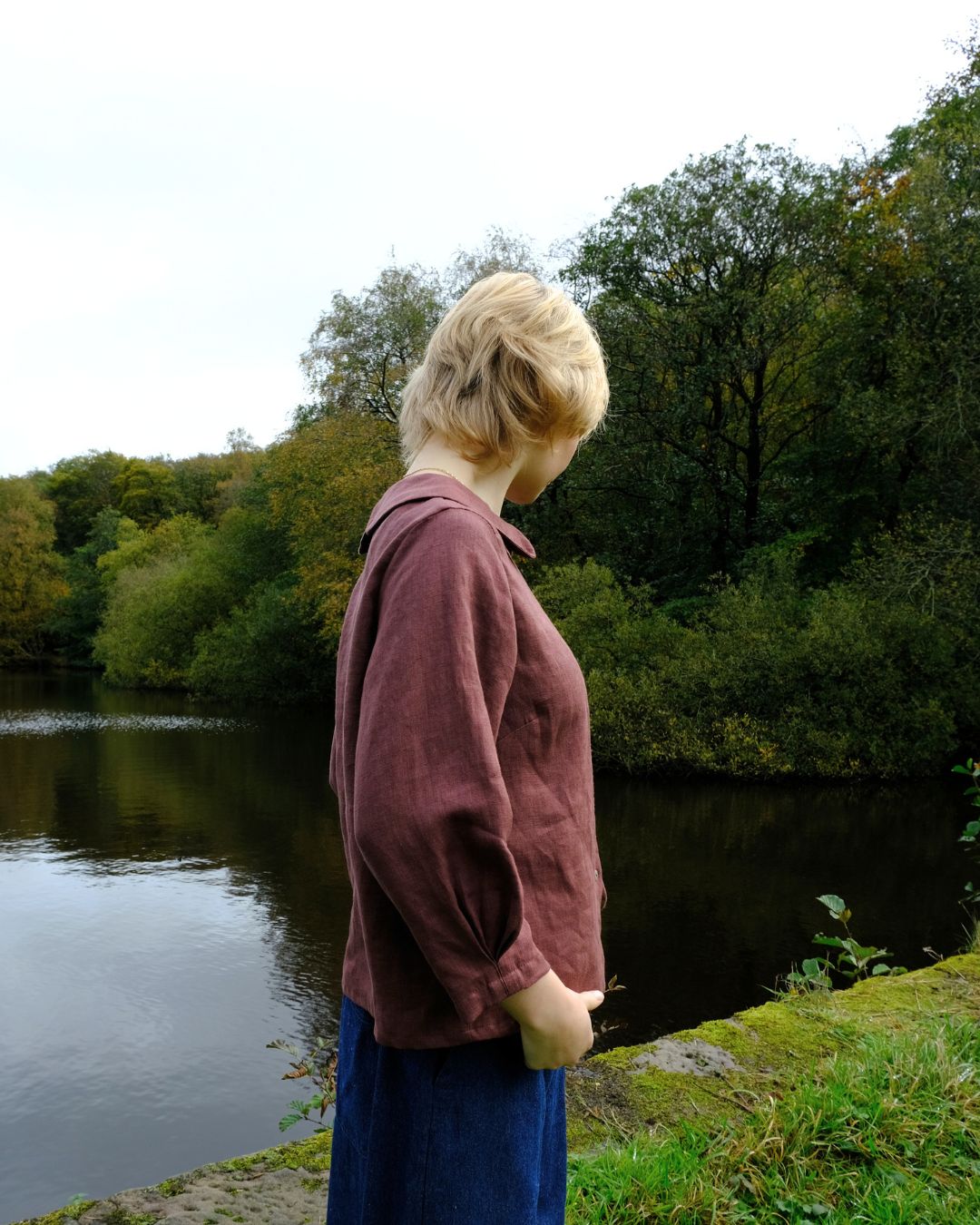 Person standing by a lake with trees in the background
