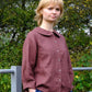 Woman wearing a maroon shirt with a collar outdoors