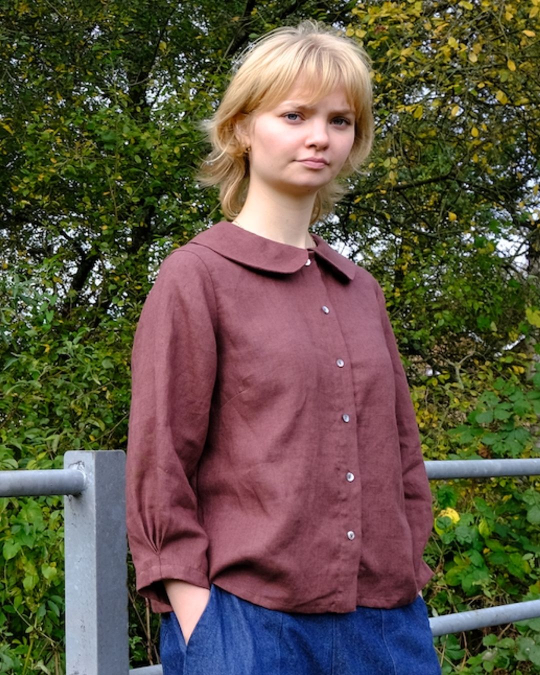Woman wearing a maroon shirt with a collar outdoors