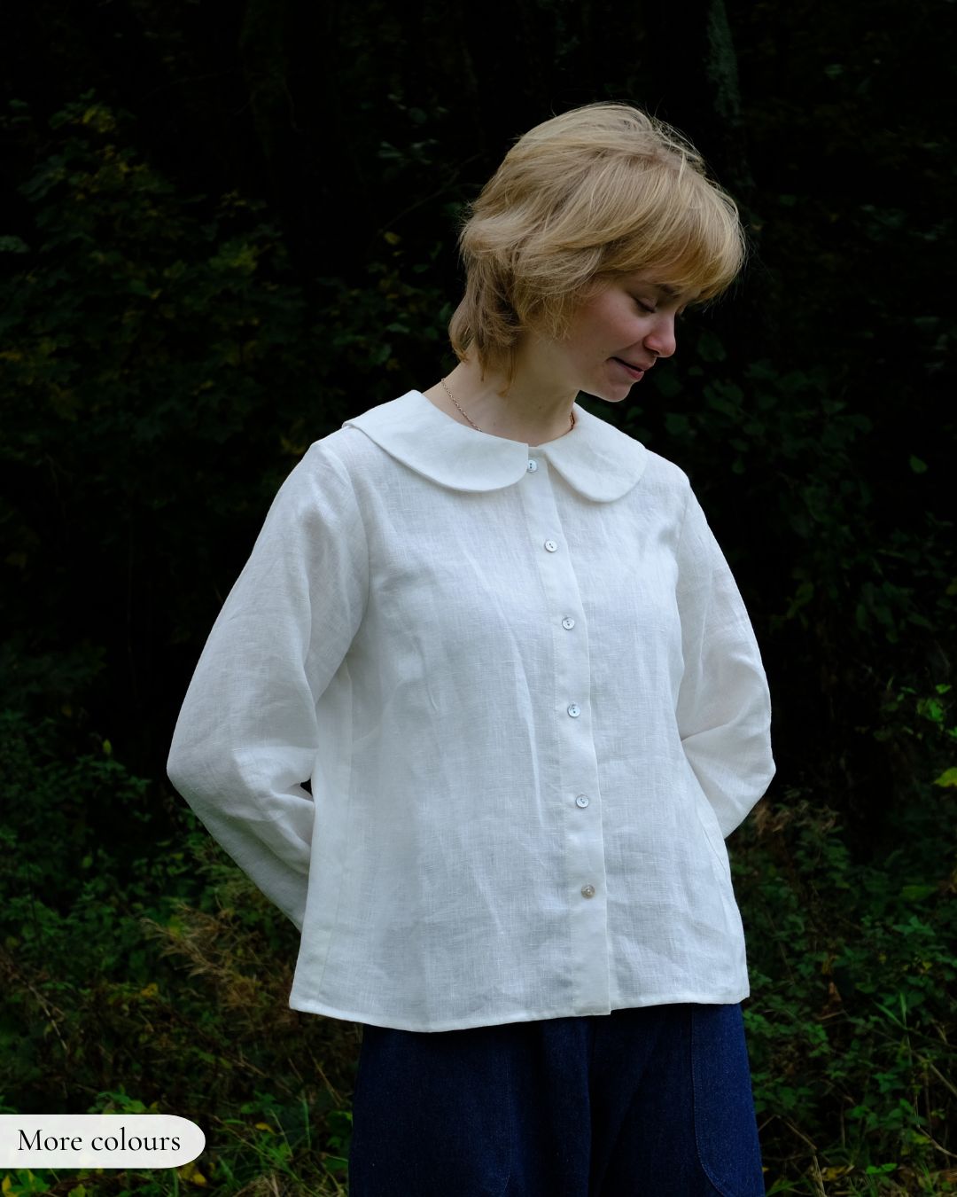 Woman wearing a white blouse with a Peter Pan collar against a dark background
