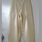 Beige pants hanging on a wooden hanger against a white wall