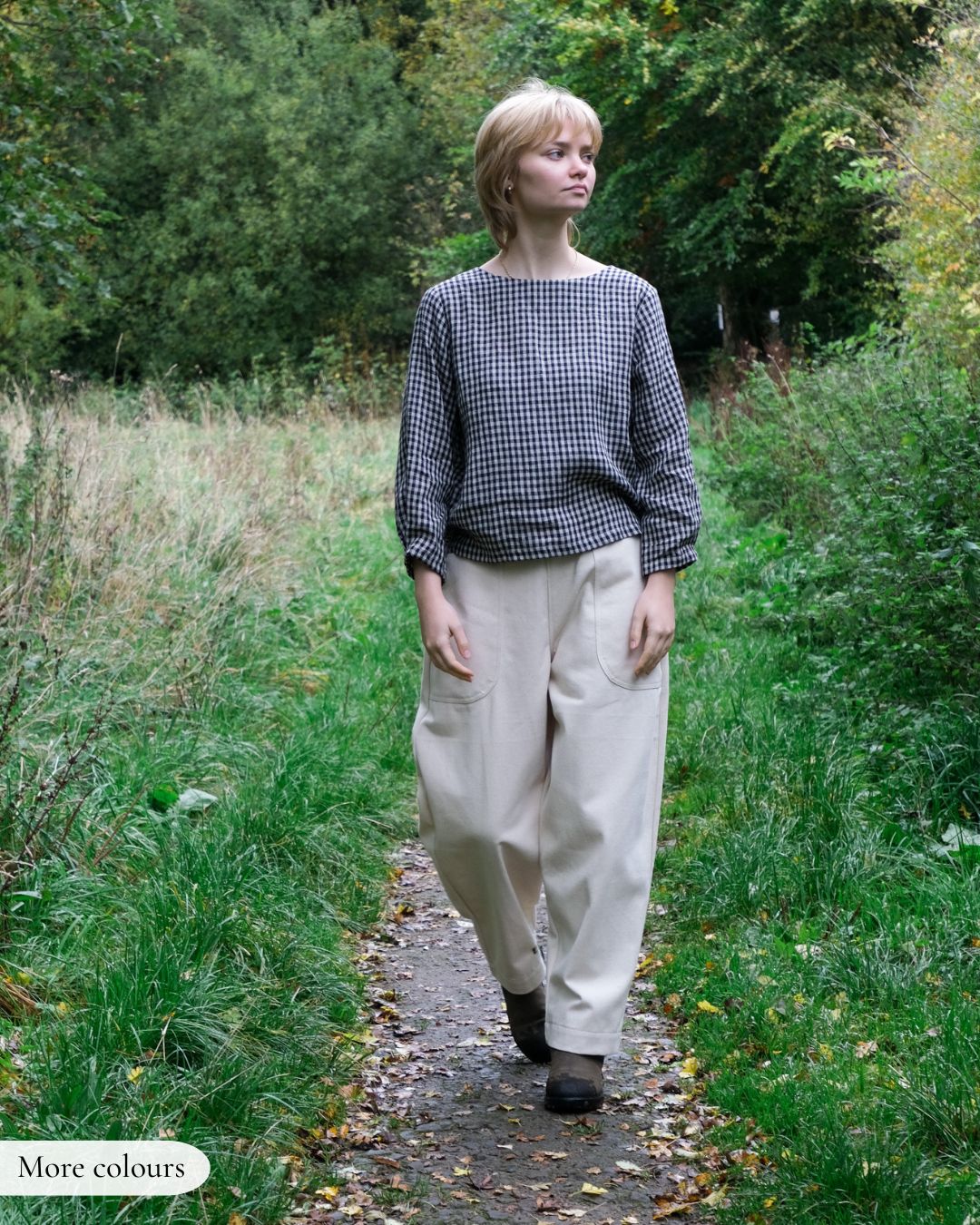 Person walking on a path in a natural setting wearing a checkered shirt and beige pants.