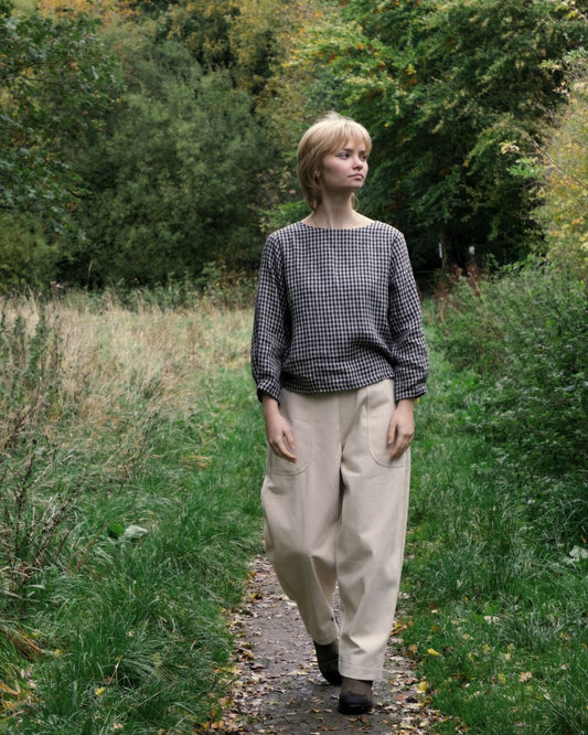Woman walking on a path in a natural setting with trees and greenery.