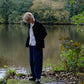 Person standing by a lake with trees in the background
