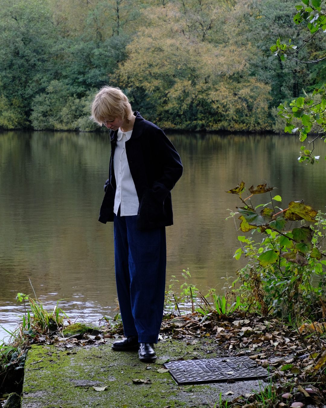 Person standing by a lake with trees in the background
