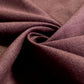 A close-up of draped fabric in a deep plum or eggplant purple color, showing the texture and weave.