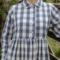 Person wearing a blue and white checkered dress outdoors.