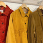 Three corduroy shirts in red, yellow, and brown hanging on a rack.