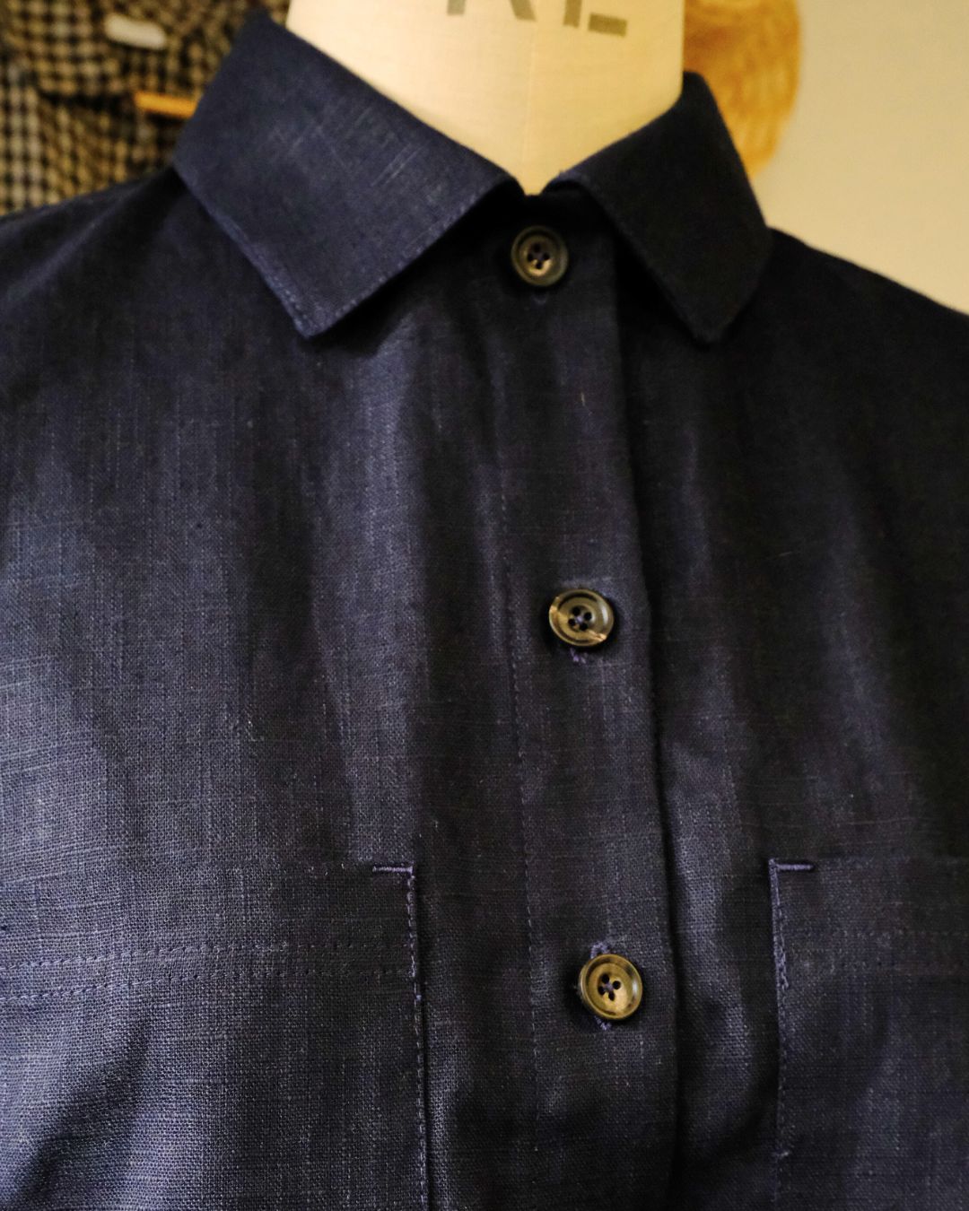 Close-up of a dark blue shirt with buttons on a mannequin against a neutral background