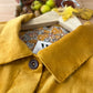 Close-up of an ochre  yellow corduroy shirt collar with a patterned fabric and autumnal elements in the background.