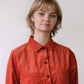 Person wearing an orange shirt against a plain background