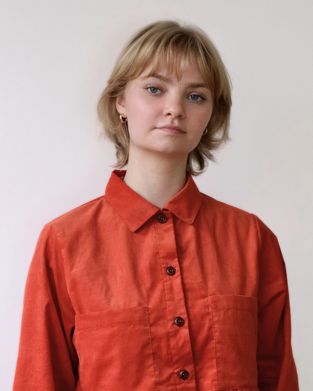 Person wearing an orange shirt against a plain background