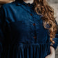 A person modeling a navy  needlecord shirt with patch pockets, a neat collar with a contrast floral print, and bracelet length sleeves finished with a cuff.