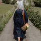Person walking down a path in a rural setting with a basket and flowers.