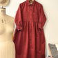 terracotta dress on a hanger with a mannequin and fabric in the background