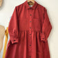 Red dress on a hanger against a white wall
