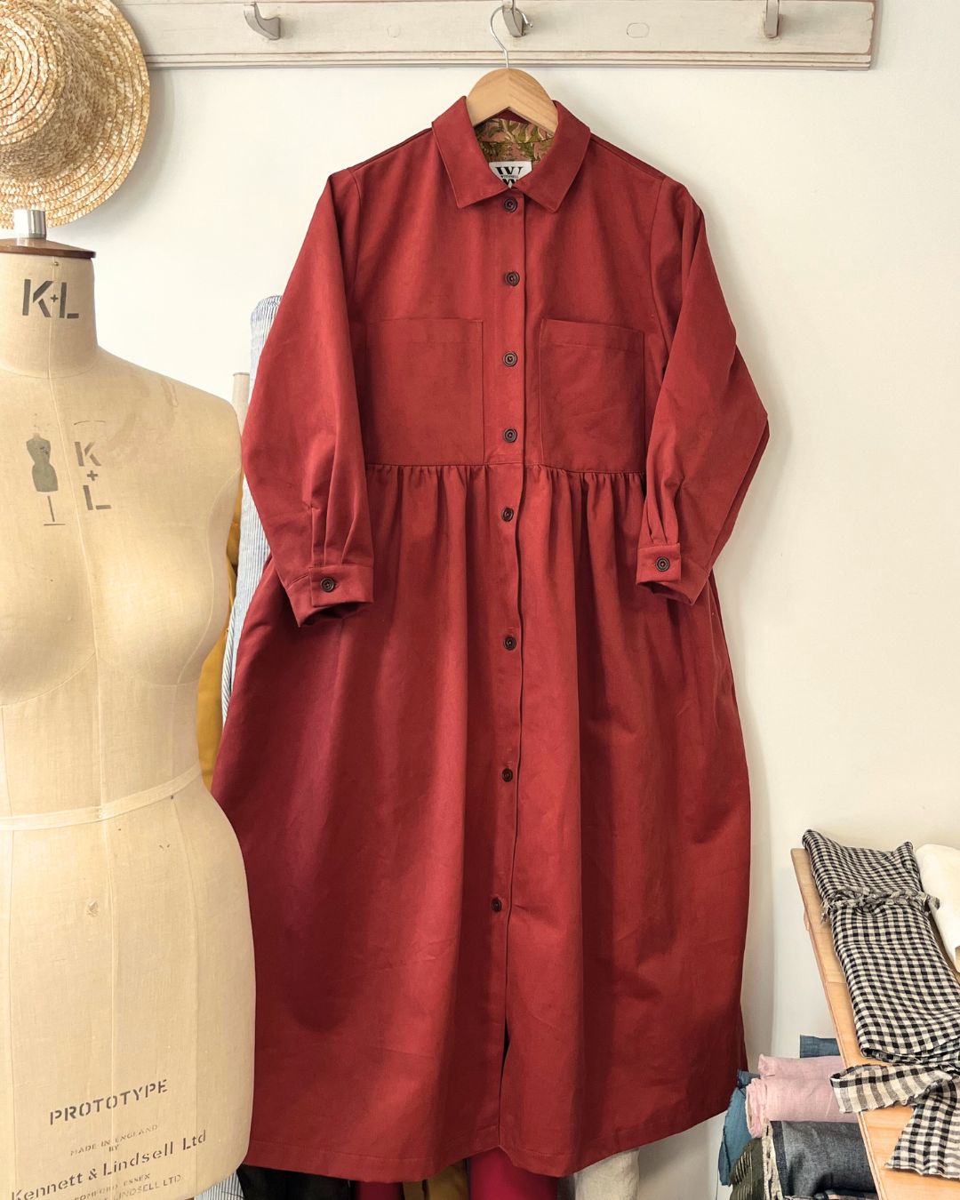 terracotta dress on a hanger with a mannequin and fabric in the background