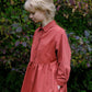 Woman wearing a red dress standing in front of green foliage