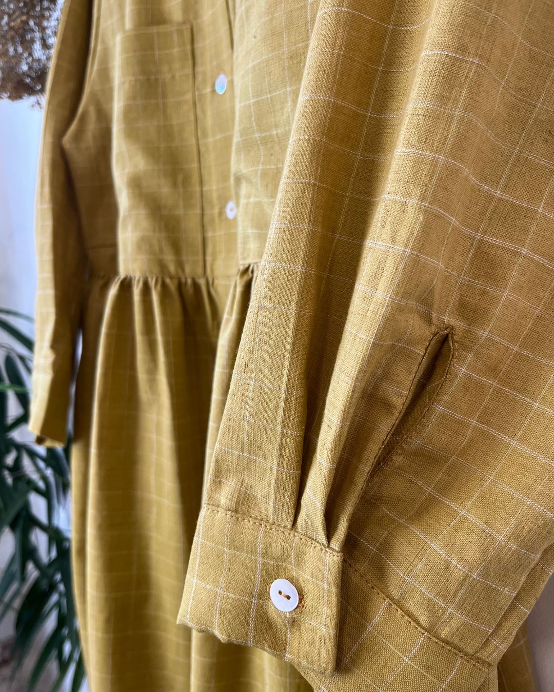 Close-up of a mustard yellow checkered dress with buttons.