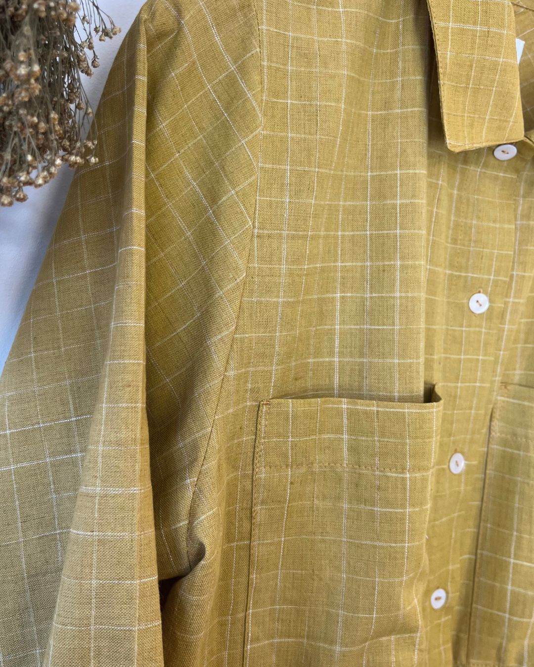 Close-up of a mustard yellow checkered shirt with a blurred background