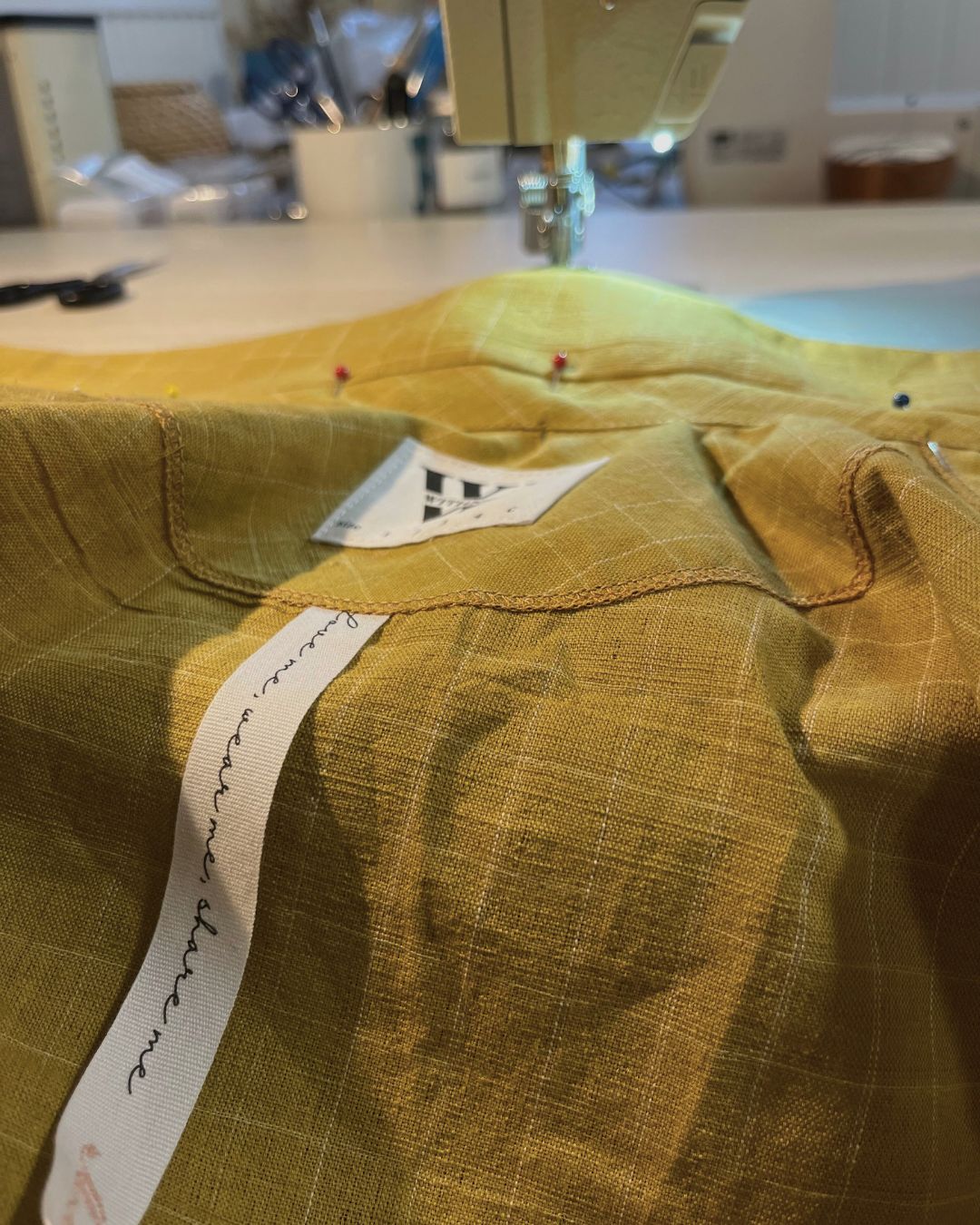 Close-up of a yellow fabric with a label on a sewing machine.